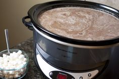 a crock pot with marshmallows in it next to a bowl of sugar