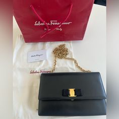 This Is An Authentic Salvatore Ferragamo Ginny Vara Bow Shoulder Bag In Black. This Chic Shoulder Bag Is Finely Crafted Of Black Patent Leather. The Bag Features A Long Gold Chain Link Shoulder Strap With A Frontal Bow Flap And A Ferragamo Ring Clasp Closure. This Opens To A Black Nylon Interior With Pocket Length: 9.50 In Width: 2.00 In Height: 6.00 In Drop: 23.00 In Elegant Gift Shoulder Bag With Original Box, Salvatore Ferragamo Bags, Walker Boots, Black Nylon, Fit N Flare Dress, Black Nylons, Boot Sandals, Black Patent Leather, Rain And Snow Boots