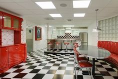 a checkered black and white floor in a kitchen with red cabinets on the wall