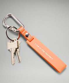 an orange keychain that says live in the moment and has two keys attached to it