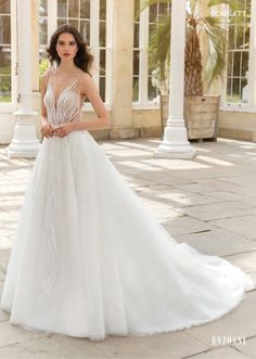 a woman in a white wedding dress standing on a stone walkway with palm trees behind her