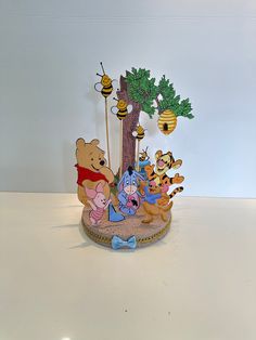 winnie the pooh figurine on display in front of a tree with honeybees