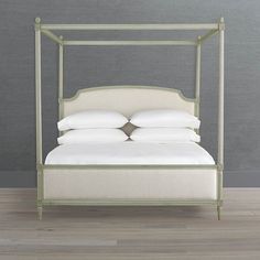 a bed with white linens and pillows on it's headboard in a room