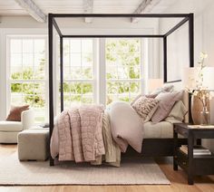 a bedroom with a four poster bed and white walls