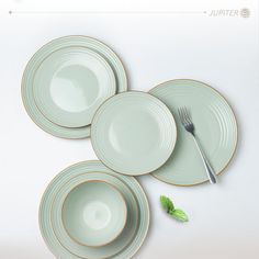 three plates and two forks on a white table with green leaves in the center, next to each other