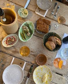 there are many plates and bowls on the table with wine, bread, and tea