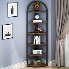 a corner shelf with books and other items on it next to a window in a blue room