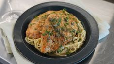 a black plate topped with chicken and pasta