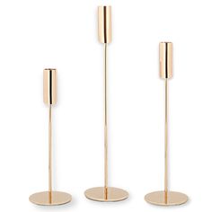 three gold - plated metal candlesticks are standing upright on each side, with one candle in the middle