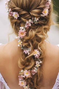 a woman with long hair and flowers in her hair is shown from the back view