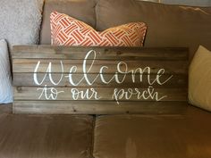 a welcome sign sitting on top of a brown couch next to pillows and throw pillows