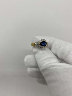 a woman's hand holding a ring with a blue stone in it