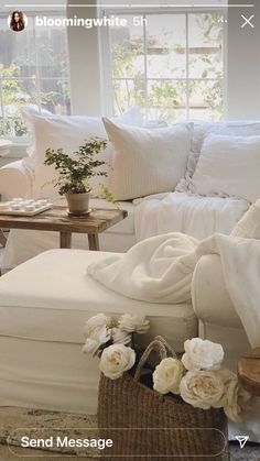 a living room filled with white furniture and flowers on the table in front of it