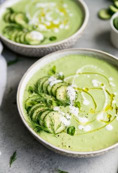 two bowls filled with green soup on top of a table