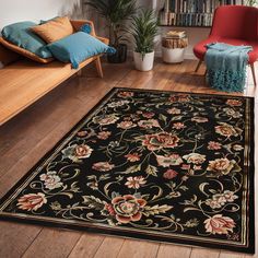 a black rug with flowers on it in a living room next to a red chair and bookshelf