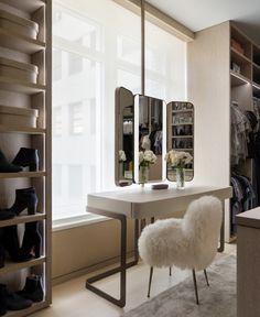 a room with a desk, mirror and shoes on the floor in front of a window