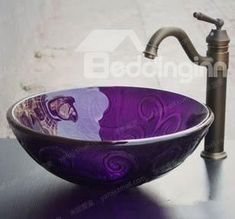 a purple glass bowl sink sitting next to a faucet on top of a counter