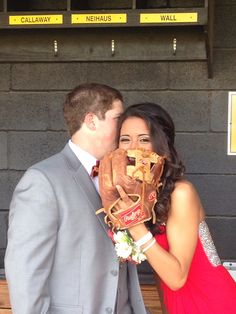 a woman in a red dress holding a catchers mitt next to a man in a gray suit