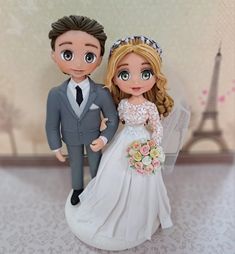 a wedding cake topper with a bride and groom in front of the eiffel tower