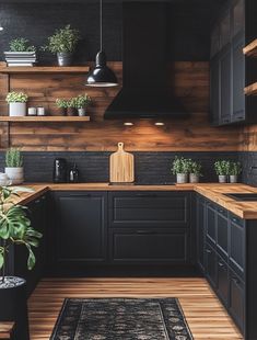 a kitchen with black cabinets and wooden shelves, plants on the counter top, and a rug in front of it