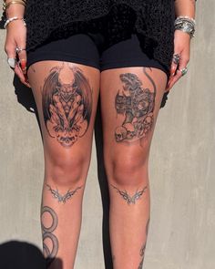 a woman with tattoos on her legs standing next to a wall