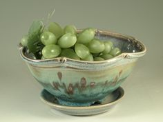 a bowl with grapes in it sitting on a saucer