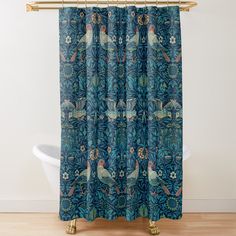 a blue shower curtain with birds and flowers in the background on a wooden floor next to a bathtub