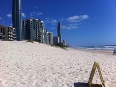 people walking on the beach with tall buildings in the backgroung and blue sky