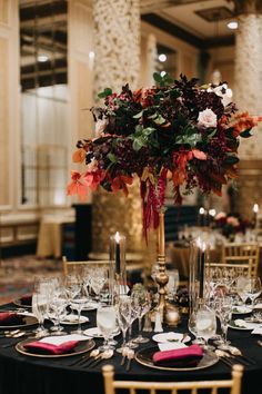 a tall vase filled with flowers sitting on top of a black table cloth covered table