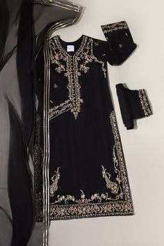 A pretty composition is layered over this elegant long silhouette on pure black cotton net. Featuring traditional paisleys with gold handwork details. Paired with embellished straight trousers and a matching ( gotah ) dupatta. A beautiful look for the festive season. Long Kameez length is 48 inches. -Fabric is pure han Black Semi-stitched Palazzo Set With Mirror Work, Party Unstitched Suit With Zari Work, Black Traditional Wear With Zari Work For Festive Occasion, Party Salwar Kameez With Dabka And Kundan Details, Party Salwar Kameez With Kundan And Dabka, Festive Black Traditional Wear With Zari Work, Festive Kundan Salwar Kameez For Party, Festive Kundan Unstitched Suit For Party, Black Dabka Kurta For Party