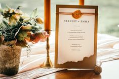 a table topped with a vase filled with flowers next to a sign that says stanley emma