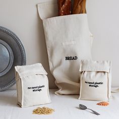 two bread baggies sitting on top of a table next to a plate and spoon