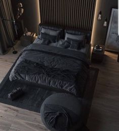 a large bed with black comforter and pillows on top of it in a bedroom