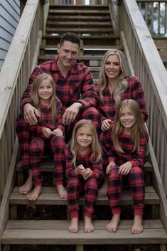 a family wearing matching red and black flannel pajamas sitting on the steps in front of their house