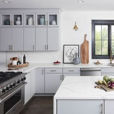 a white kitchen with stainless steel appliances and counter tops, along with an island in the middle