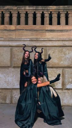 three women dressed up in costumes posing for a photo with horned horns on their heads