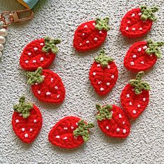 crocheted strawberries are arranged on the floor next to a beaded keychain