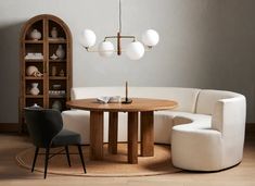 a living room with a round table surrounded by white chairs and bookshelves in the corner