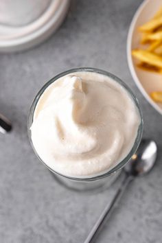 a glass bowl filled with whipped cream next to french fries