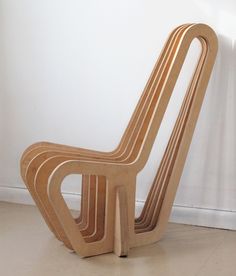 a wooden chair sitting on top of a floor next to a white wall with a window behind it