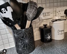 black and white kitchen utensils in a spider web canister