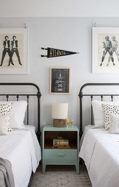 two twin beds in a bedroom with pictures on the wall above them and an end table