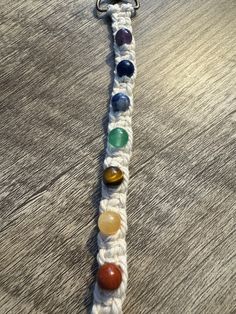 a white bracelet with seven chakras on the end and one bead at the end