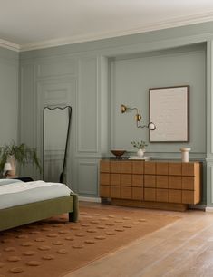 a bedroom with a bed, dresser and mirror on the wall next to each other