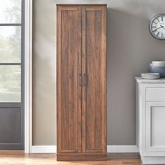 a large wooden cabinet sitting in the corner of a room with a clock on the wall