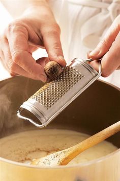 a person grating something in a pot with a wooden spoon