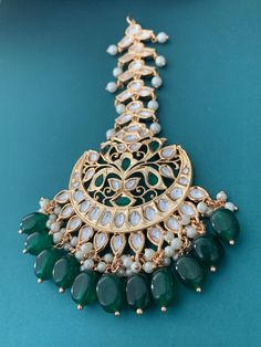 Tyanni kundan Tikka in green. Medium to oversize. About 4 inch vertically and 4 horizontally. Unique design and completely gold plated. Drops are all glass crystal. Band is also about an inch wide. Festive Green Tilla Tikka, Green Hand Set Tikka As A Gift, Green Bollywood Tikka For Festive Occasions, Green Bollywood Style Tikka For Festive Occasions, Elegant Green Tikka For Festive Season, Elegant Green Tikka For Festive Occasions, Festive Green Bollywood Tikka, Green Chandbali Tikka For Festive Occasions, Festive Green Chandbali Tikka