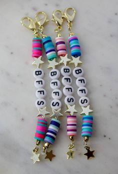 several bracelets with stars and letters are hanging on a marble countertop in front of a keychain