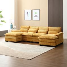 a living room with a large yellow couch and white rug on the wooden flooring