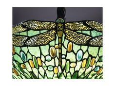 a stained glass lamp with dragonflys on it's wings and green leaves